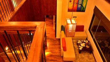 Un interior moderno con una escalera de madera, una zona de estar con una mesa y un cuadro abstracto colorido en la pared.