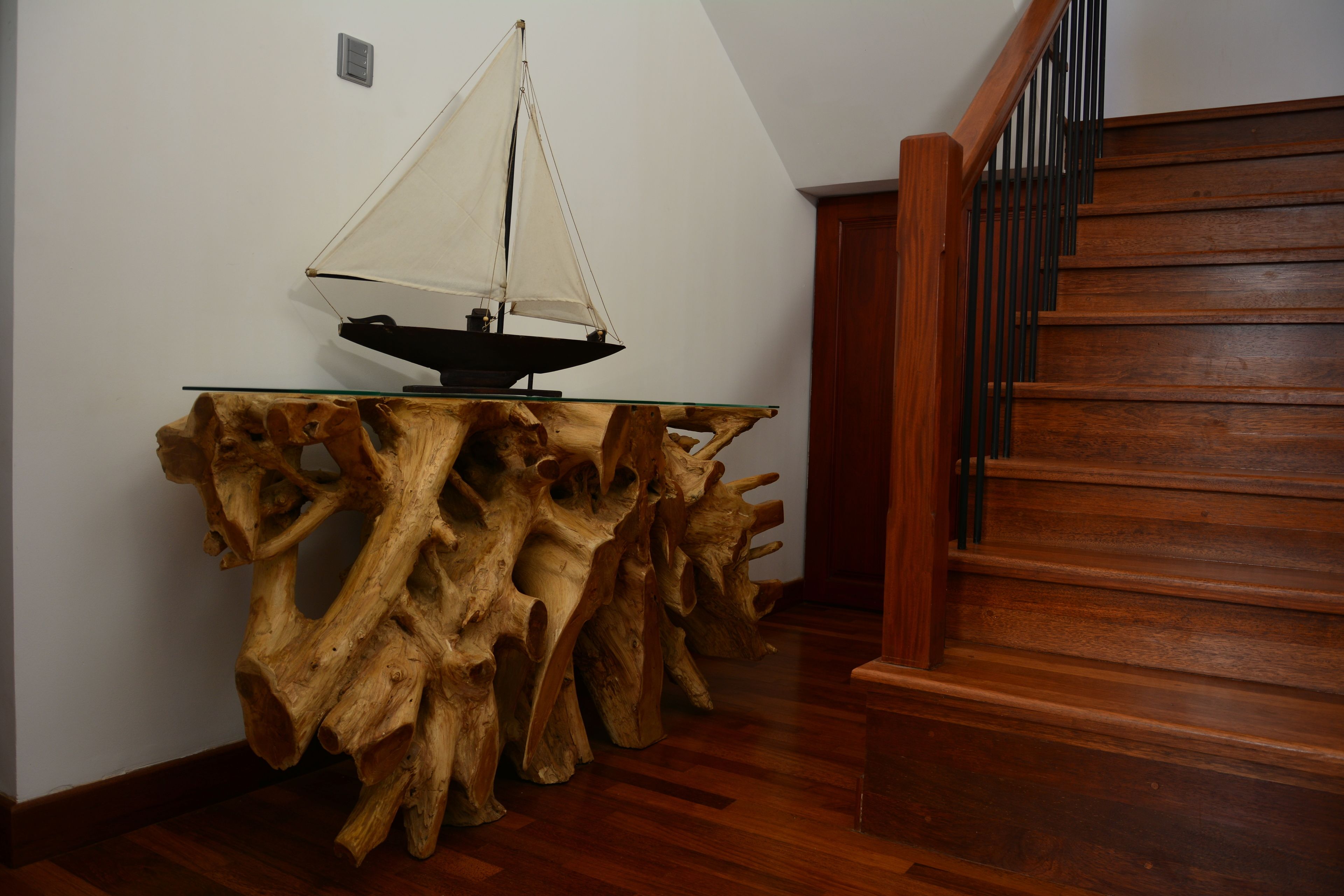 Una escalera de madera con barandilla, una mesa original con un modelo de velero, y un aplique de pared.