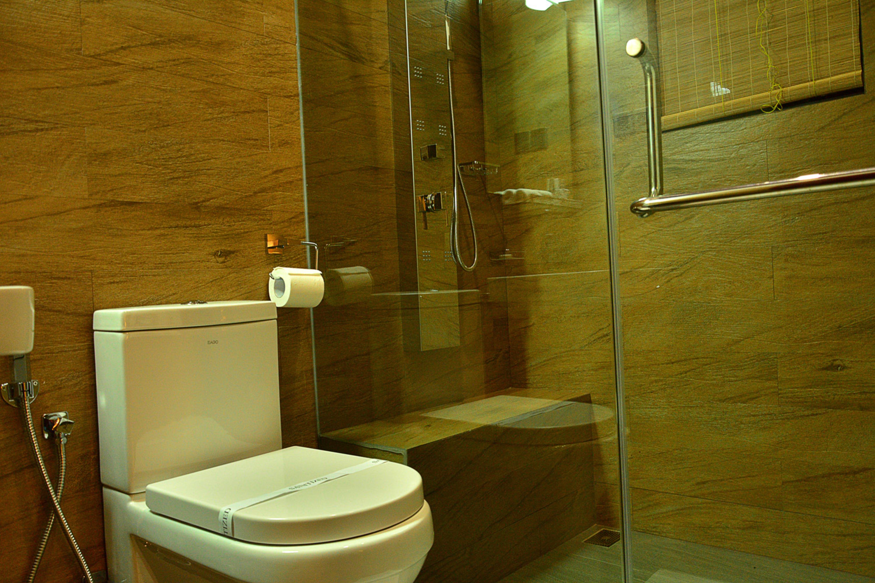 Un baño moderno con ducha de vidrio, inodoro y barandilla.