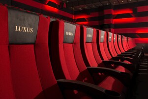 Filas de asientos rojos y negros con la marca 'LUXUS', que indican una zona de asientos de alta gama.