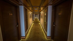 Un pasillo de hotel con puertas numeradas 508 y 509, cubierto con alfombra de diseño geométrico, y cuadros en las paredes.