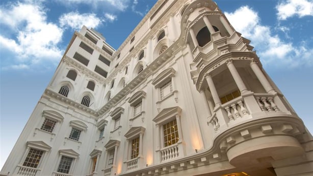 Un edificio grande y blanco con varios pisos, amplias ventanas y detalles arquitectónicos clásicos.