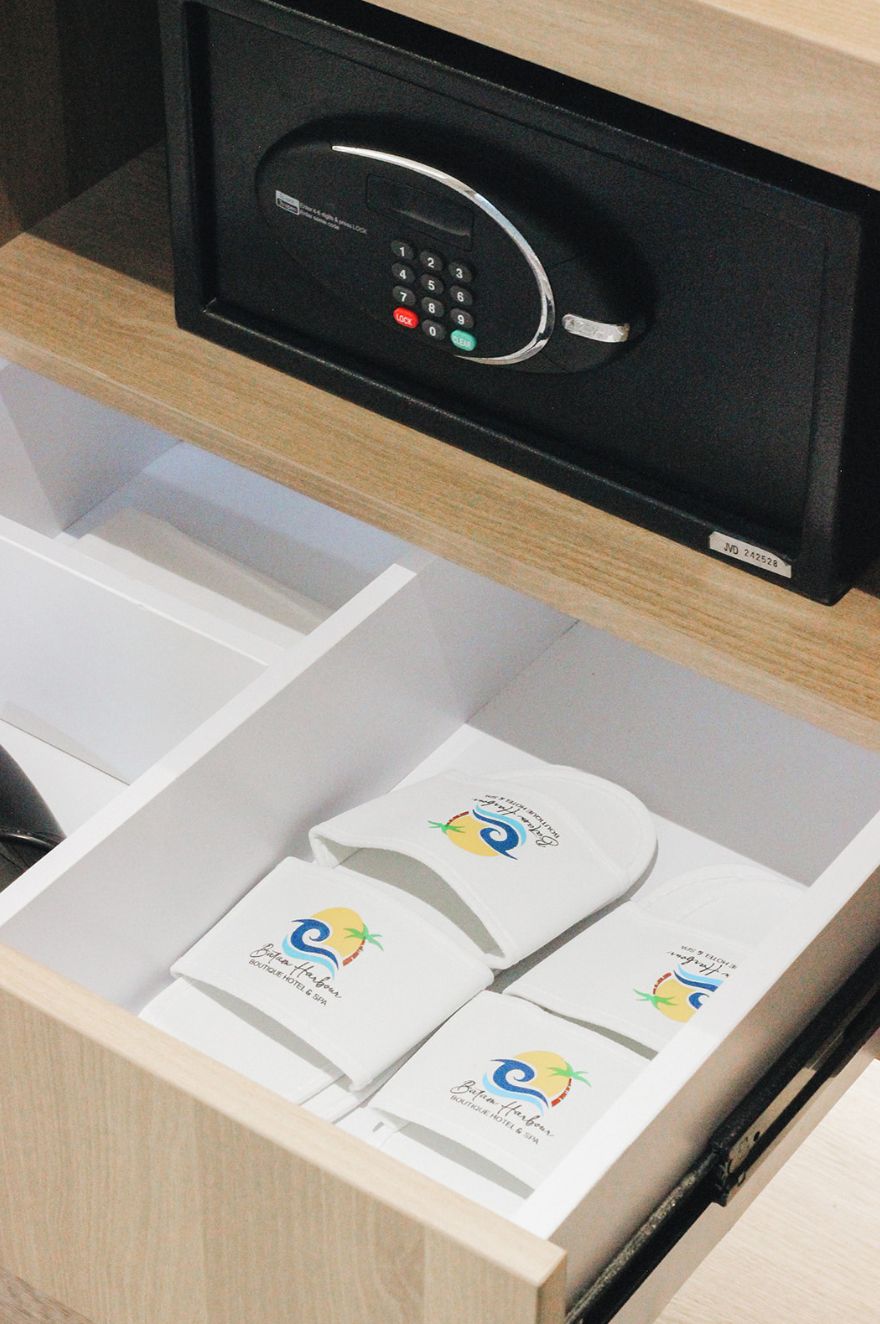Un tiroir contenant un appareil électronique noir, qui pourrait être un coffre-fort, ainsi que plusieurs cartes blanches ornées d’un logo.