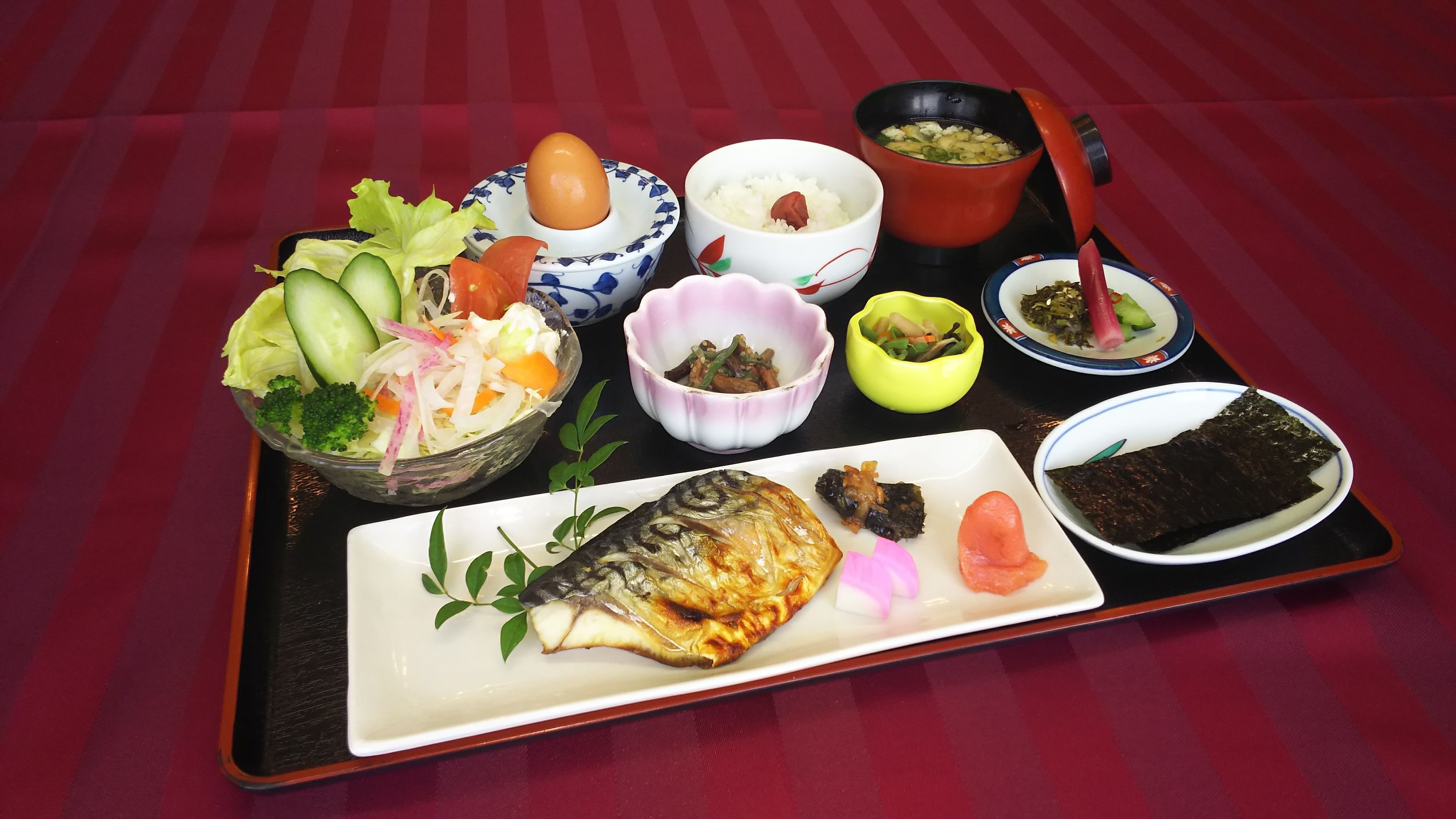 A tray with various Japanese dishes including sushi, rice, and vegetables.
