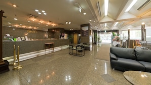 Un hall de hotel con mostrador de recepción, zona de estar y un sofá.