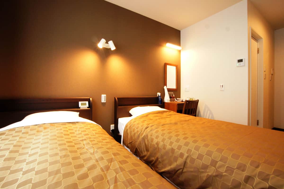 Une chambre d’hôtel avec deux lits, un bureau et une chaise.