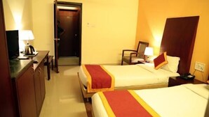 Ein Hotelzimmer mit zwei Betten, einem Schreibtisch, einem Stuhl und einer Tür.