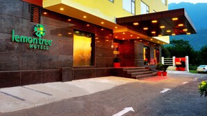 Una entrada de hotel moderna con un letrero llamativo, un corredor cubierto y un área de estacionamiento.
