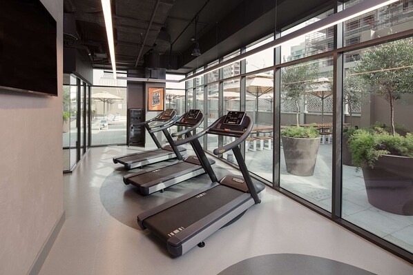 A modern gym with treadmills, large windows, and indoor plants. - Rove City Centre, Deira (Dubai)