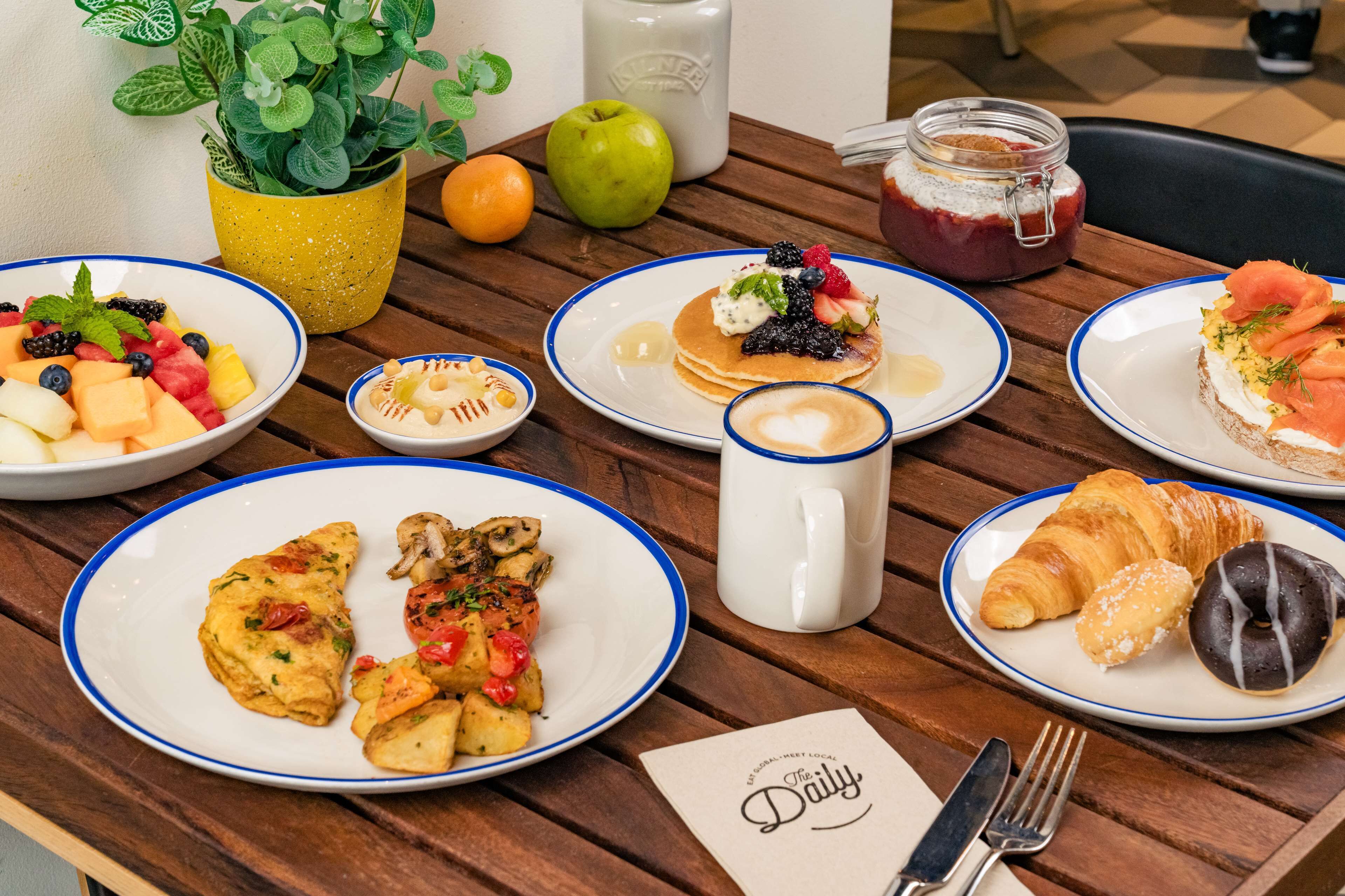 A breakfast table with various dishes, including pancakes, croissants, and fruit.