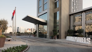 L’entrée d’un hôtel moderne, avec une grande enseigne, un drapeau et un ciel dégagé.
