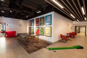A modern conference room with a ping pong table, framed artwork on the walls, and red chairs.