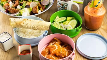 A table with various dishes including a salad, rice, curry, and a smoothie.