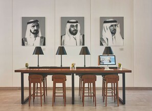 A modern office space with a long table, four wooden chairs, three black lamps, and a computer monitor displaying a website. - Rove City Centre, Deira (Dubai)