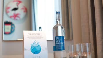 Une bouteille d’eau avec une étiquette, un verre et un panneau sur une table.