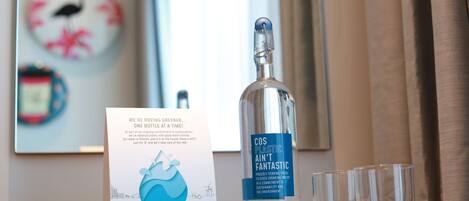 A bottle of water with a label, a glass, and a sign on a table.