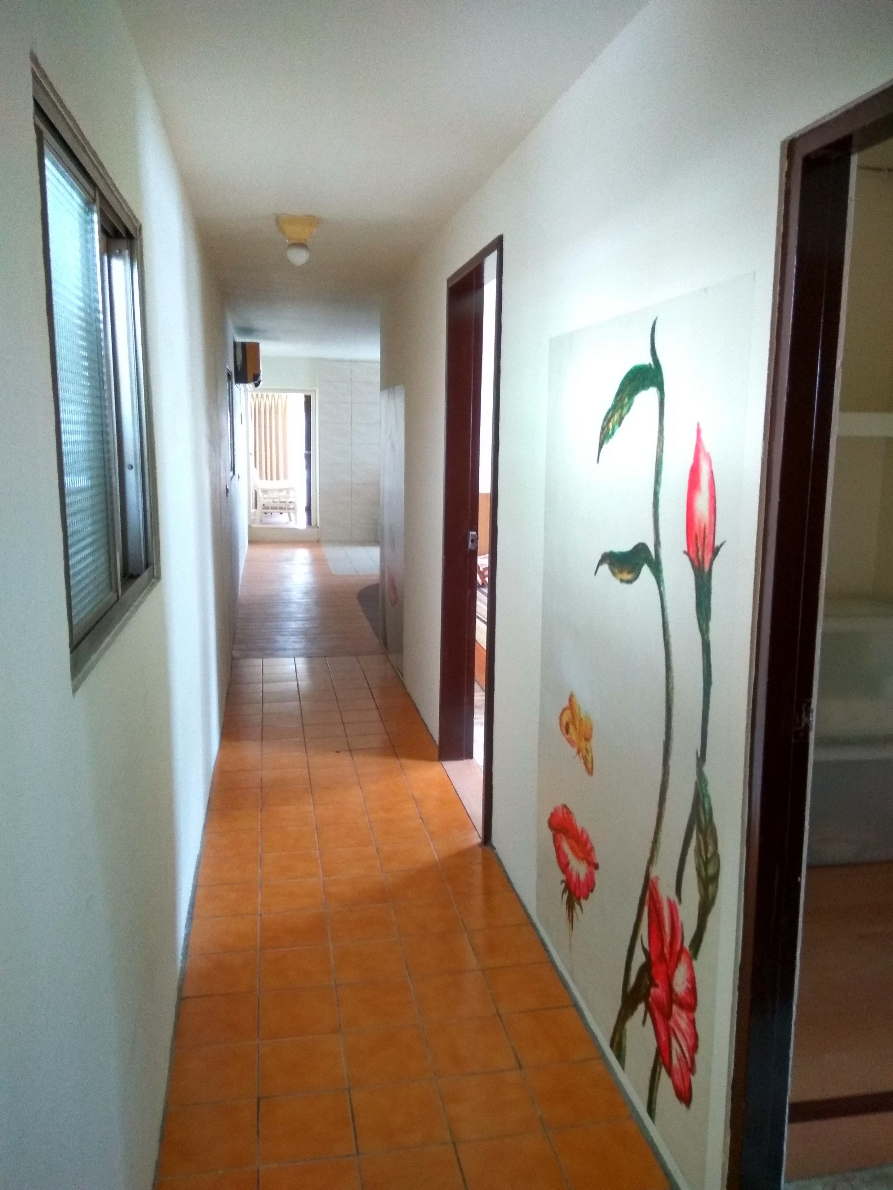 A hallway with tiled flooring and a wall with floral artwork.