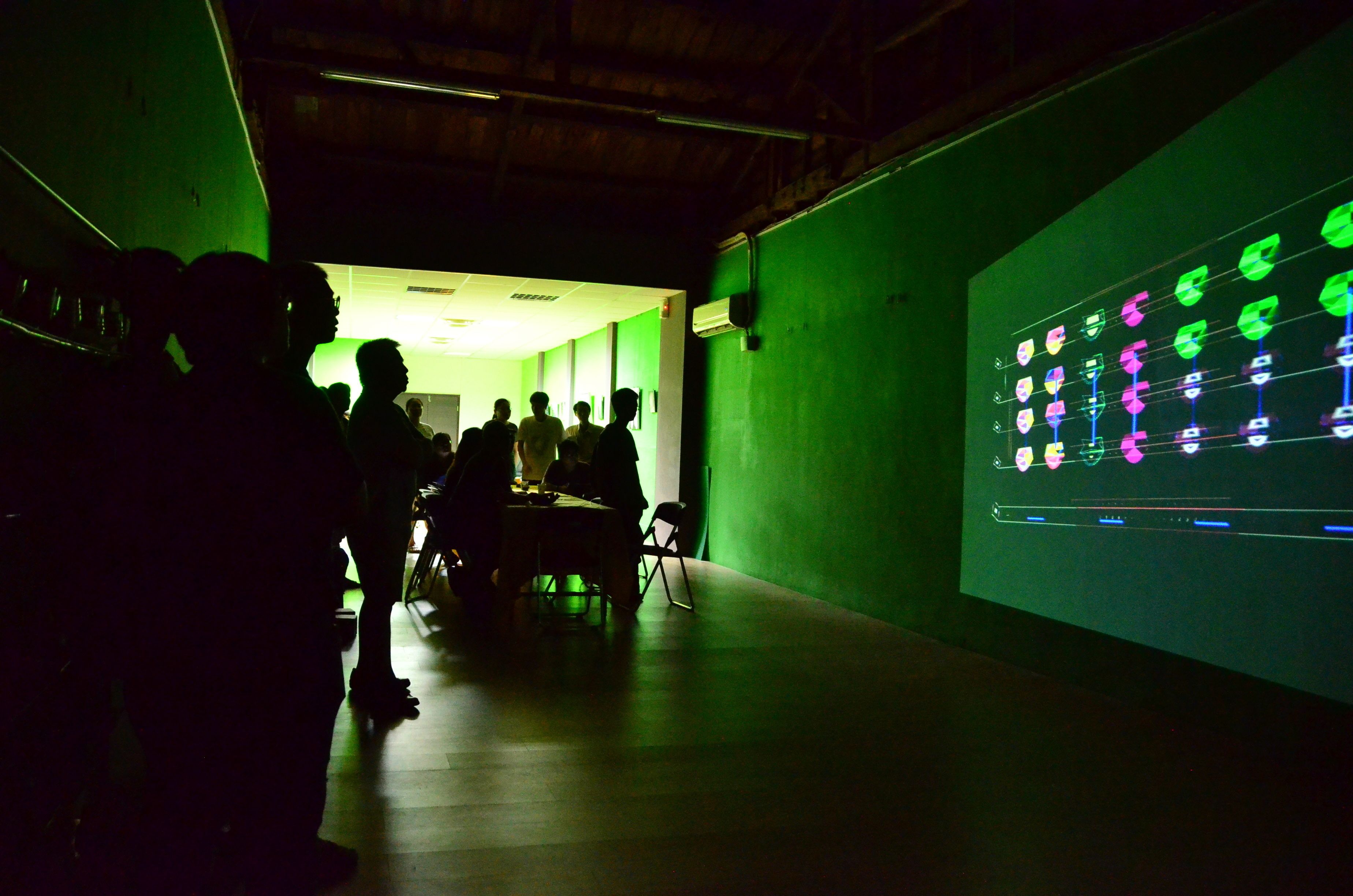 Un pasillo tenuemente iluminado con una pantalla proyectando iconos de colores.