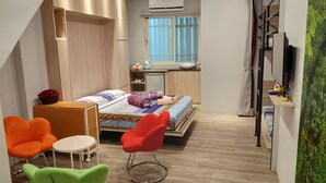 Een kleine hotelkamer met een bed, een bureau, een stoel en een televisie.