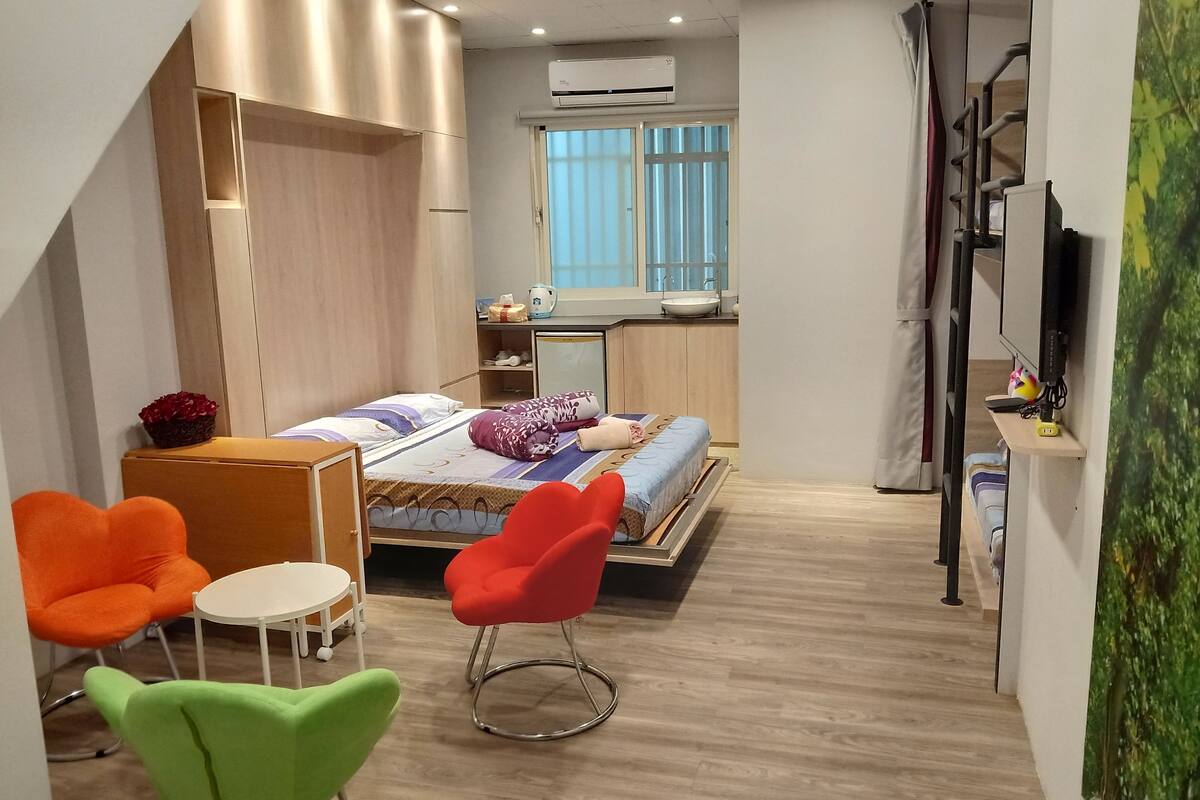 Habitación de hotel compacta con cama, escritorio pequeño, una silla y televisor.