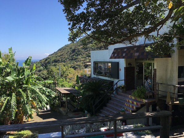 A modern building with a balcony, a staircase, and a view of a lush green landscape. - Villa Shirahama (Shimoda)