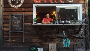 Eine rustikale Holztheke mit einem Schild für Craft Beer, einer Speisekarte und einem Barkeeper.
