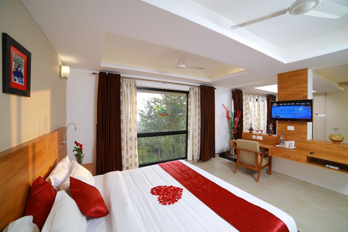 Habitación de hotel con una cama, un escritorio, un televisor y un ventanal con cortinas.