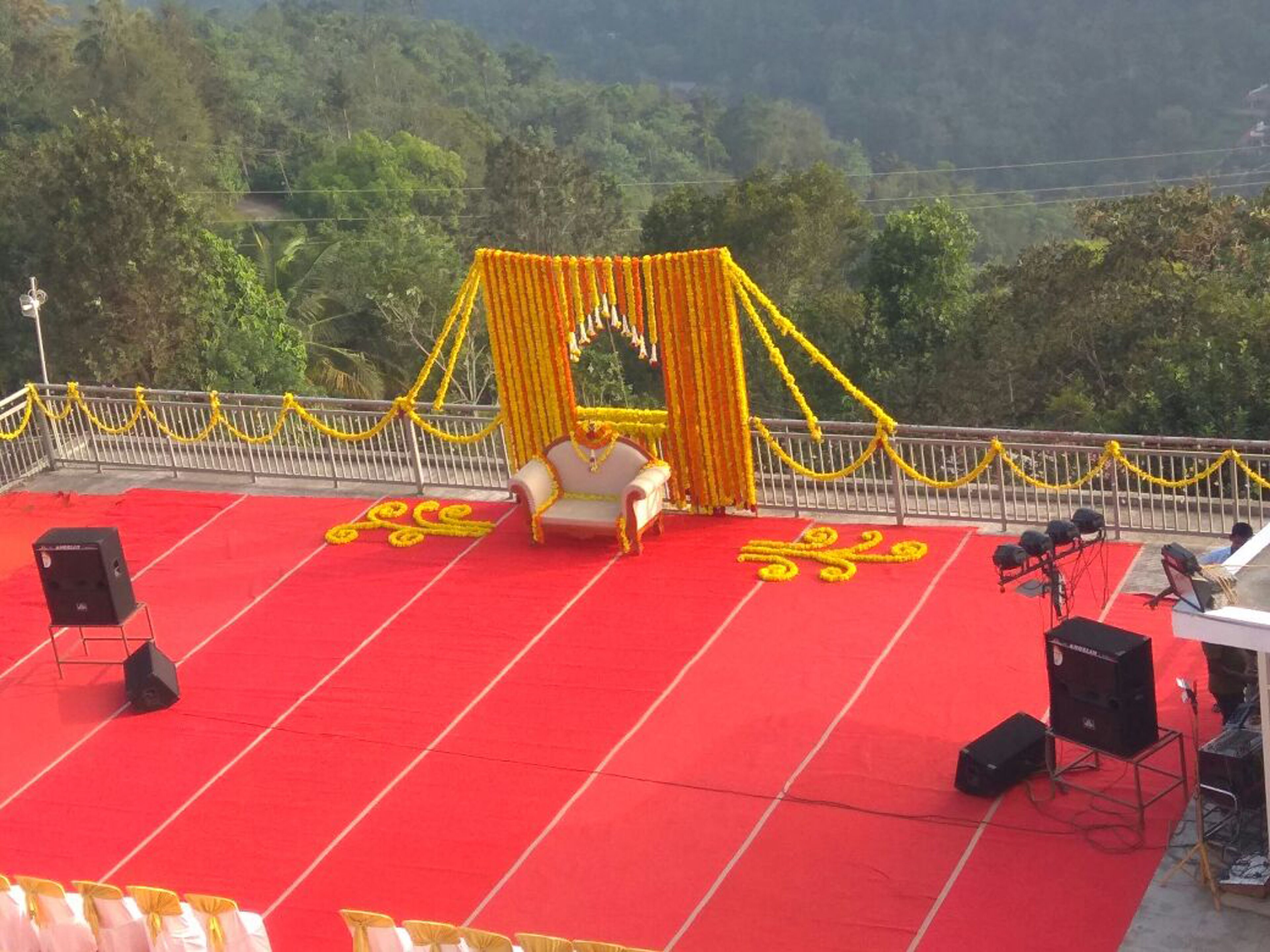 A stage with a red carpet, a white sofa, and yellow floral decorations.