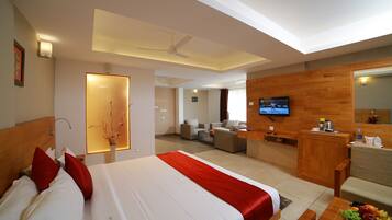 Una habitación de hotel con cama, escritorio, televisión y zona de estar.