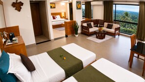 Ein Hotelzimmer mit zwei Betten, einer Sitzecke inklusive Sofa und Sesseln, einem Esstisch und Blick ins Freie.
