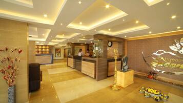 A hotel reception area with a modern design, featuring a reception desk, a clock, and a decorative wall piece.