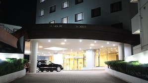 A hotel entrance with a car parked in front, a glass door entrance, and a sign above the entrance. - Plaza Hotel Shimonoseki (Shimonoseki)