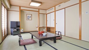 A traditional Japanese tatami room with a tatami mat floor, a low table, and a television on a stand. - Plaza Hotel Shimonoseki (Shimonoseki)