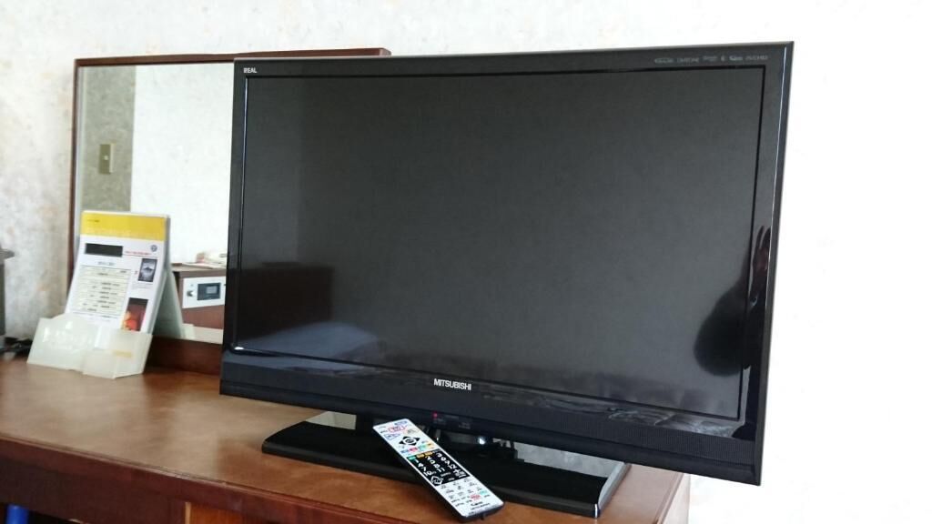 A Mitsubishi flat-screen TV on a wooden stand.