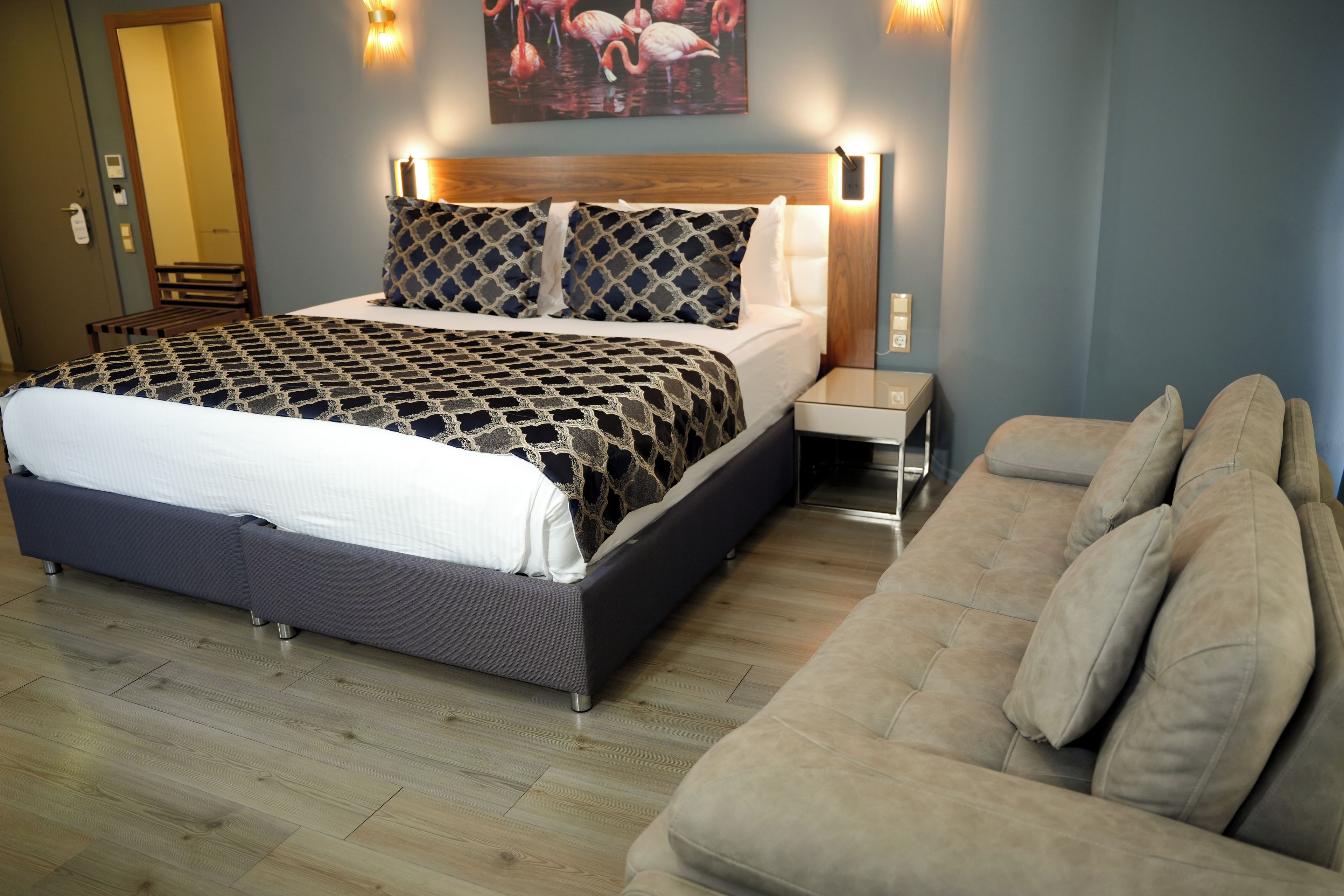 Un dormitorio moderno con una cama grande, una mesita de noche, un sofá y un cuadro en la pared.