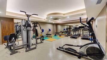Un gimnasio con diversos equipos de ejercicio, incluyendo cintas de correr y máquinas de pesas.
