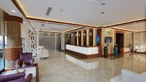 A spacious lobby with a reception desk, seating area, and decorative elements. - Forum Suite Hotel (Mersin)