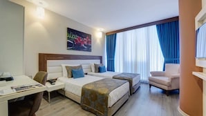 A hotel room with two beds, a desk, a chair, and a TV. - Forum Suite Hotel (Mersin)
