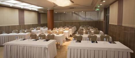 Un salón de conferencias con varias mesas, sillas y botellas de agua.