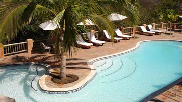 Una piscina al aire libre, sombrillas, tumbonas