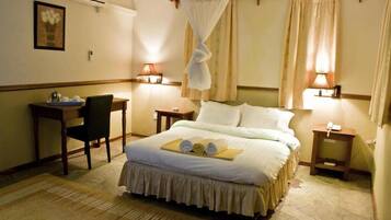Una habitación de hotel con una cama, mesitas de noche, un escritorio y una silla.
