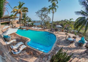 Una piscina al aire libre, sombrillas, sillones reclinables de piscina