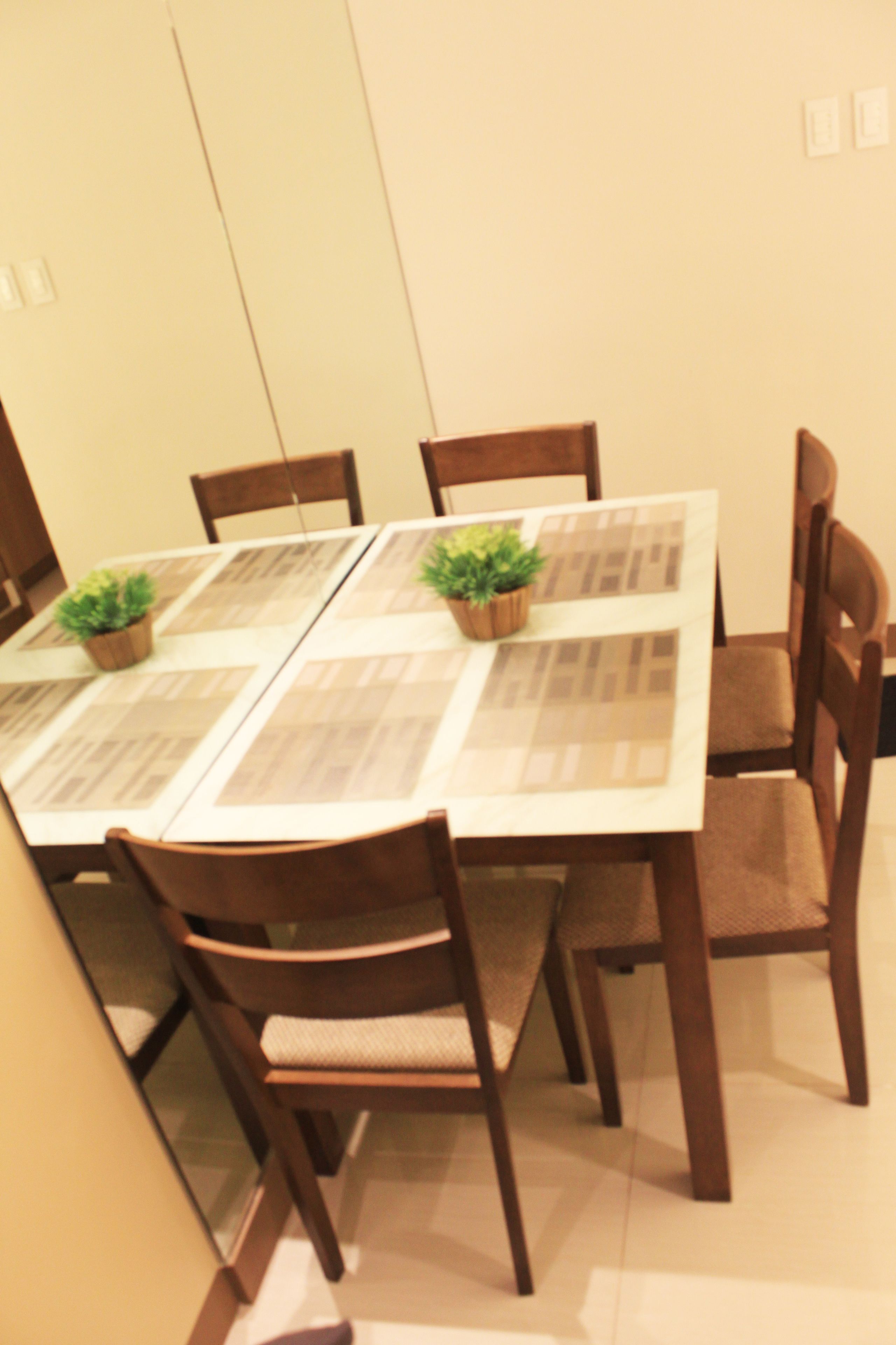 A dining table with a placemat, surrounded by wooden chairs.