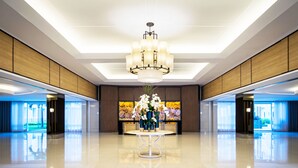 A lobby with a chandelier, a round table with vases, and a large floral wall mural. - Shell Residences Apartment by Homebound (Pasay)