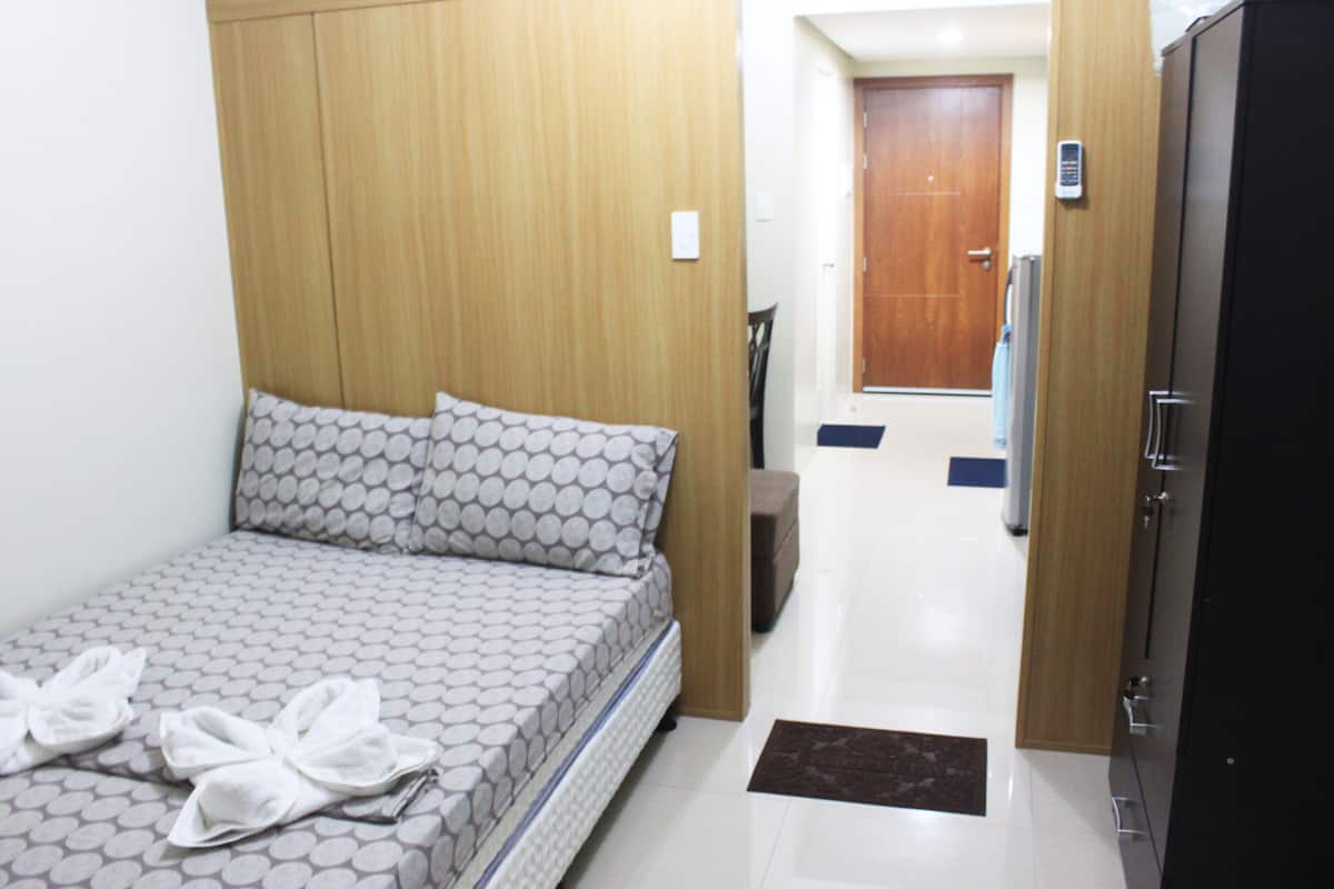 A hotel room with a bed, wardrobe, and a door leading to a hallway.
