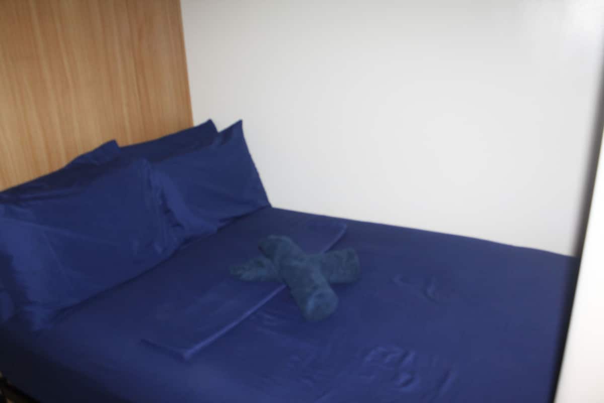 A bed with blue bedding and a teddy bear on it.