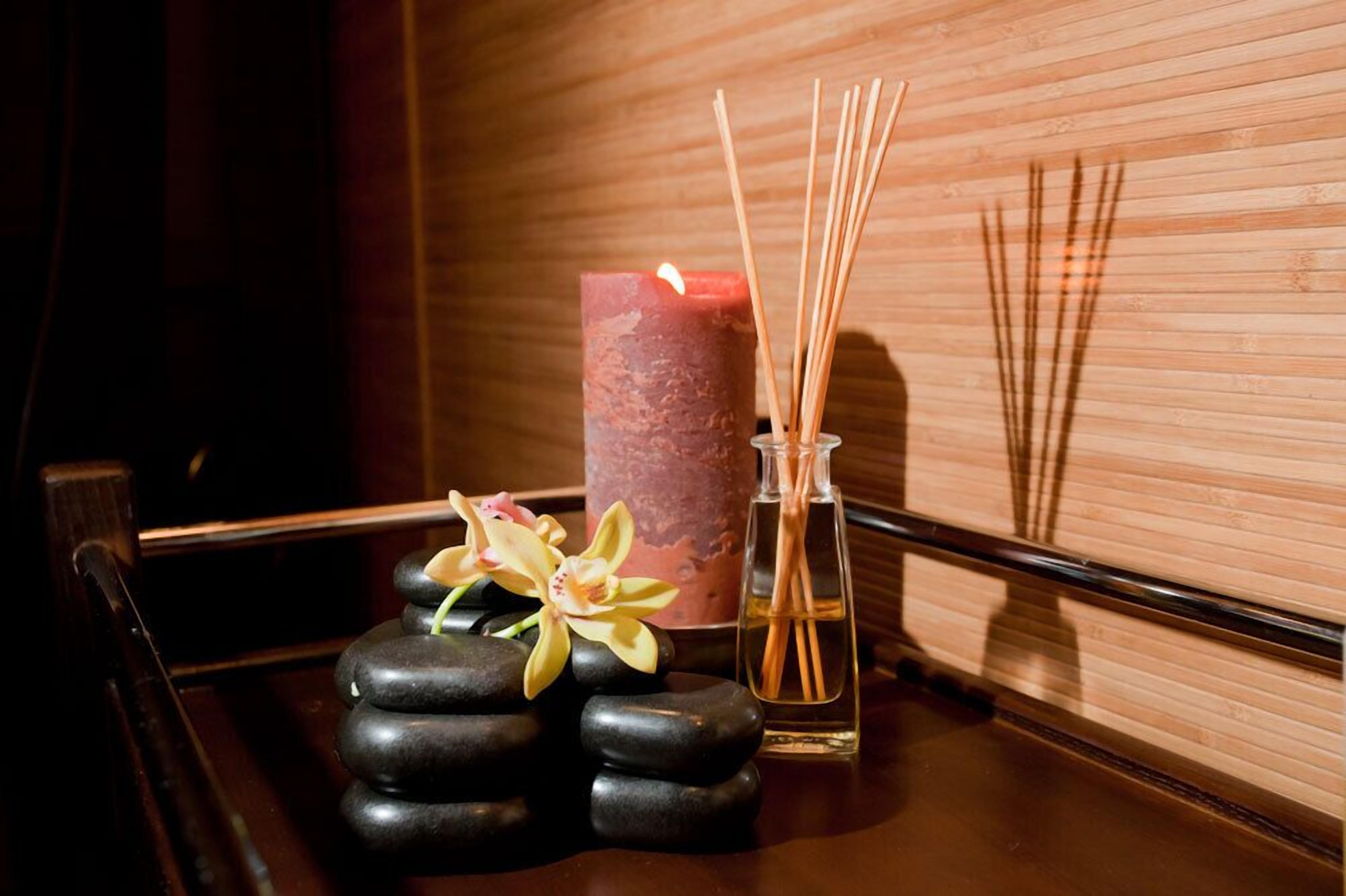 Una candela, bastoncini di incenso e un fiore su un piano di legno.