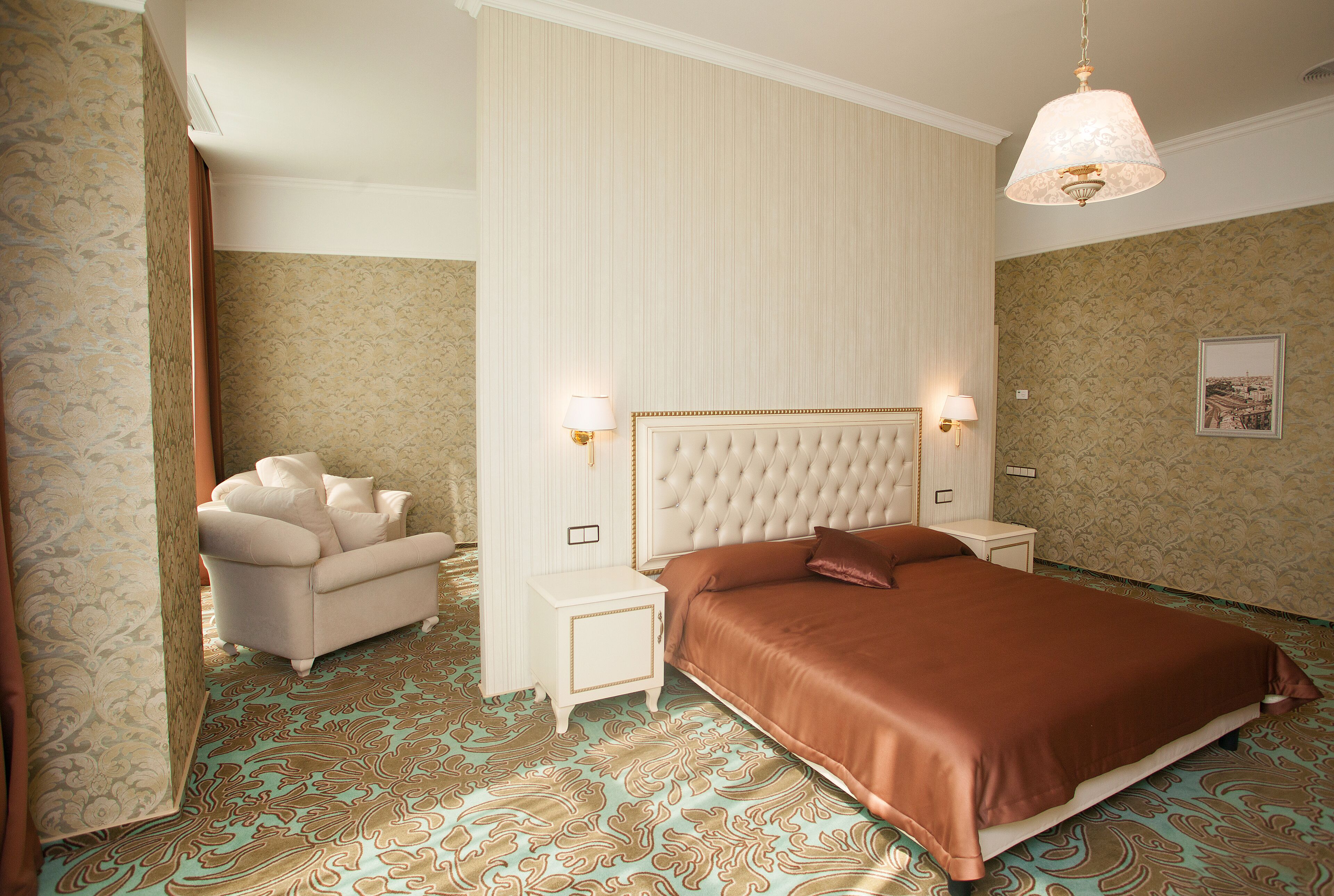 A bedroom with a large bed, a nightstand, a chair, and a patterned carpet.