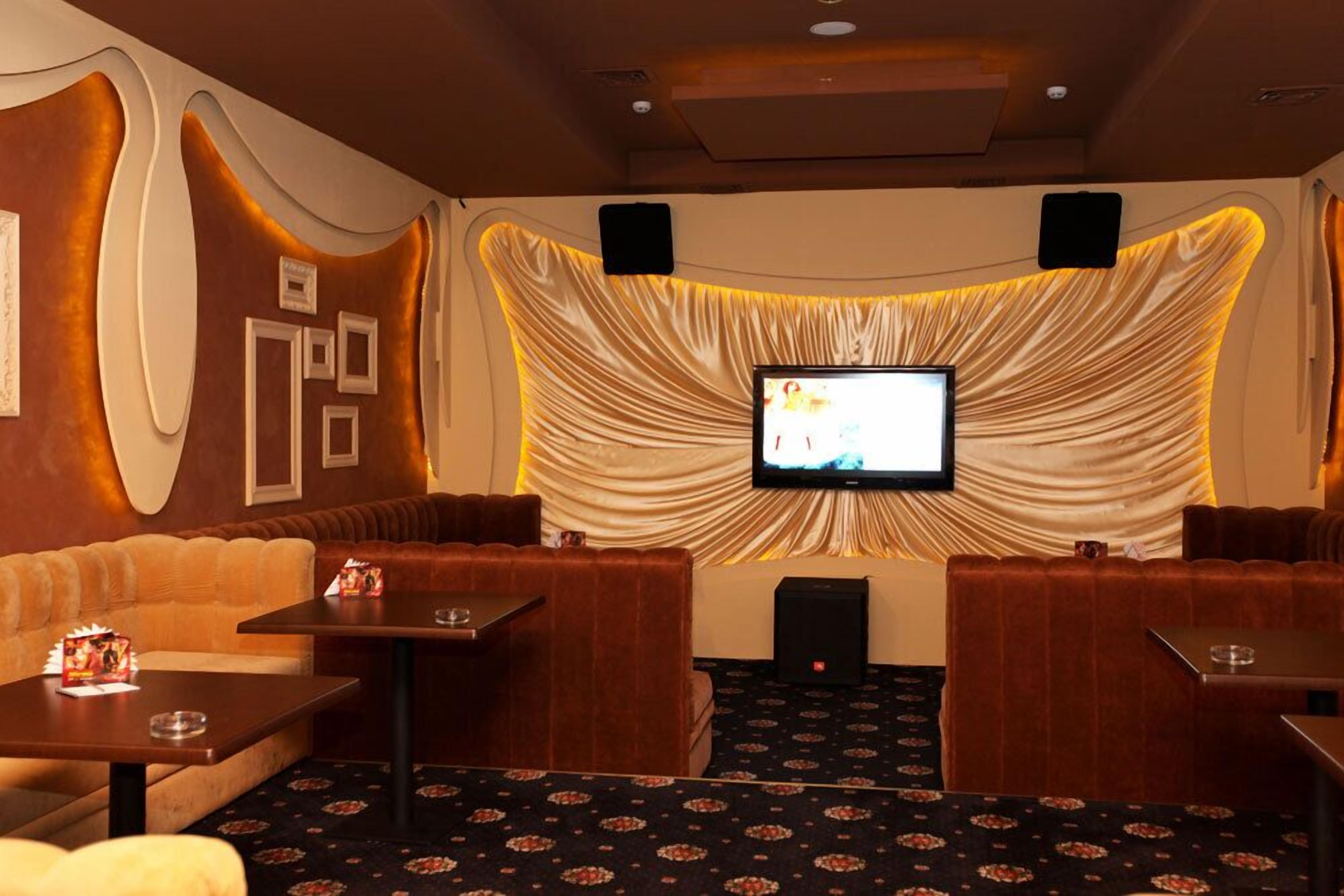 A cinema room with a large screen, plush seating, and a carpeted floor.