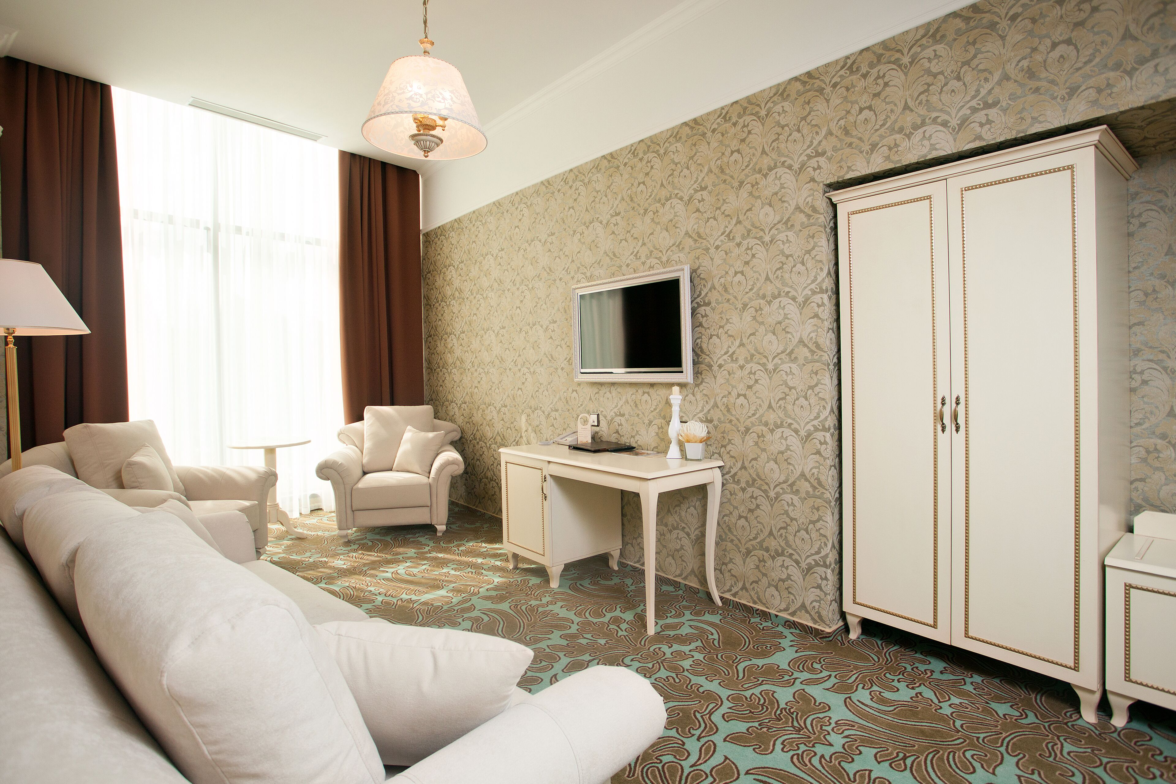 Ein Hotelzimmer mit einer großen Couch, einem kleinen Tisch, einem Fernseher und einem Kleiderschrank.